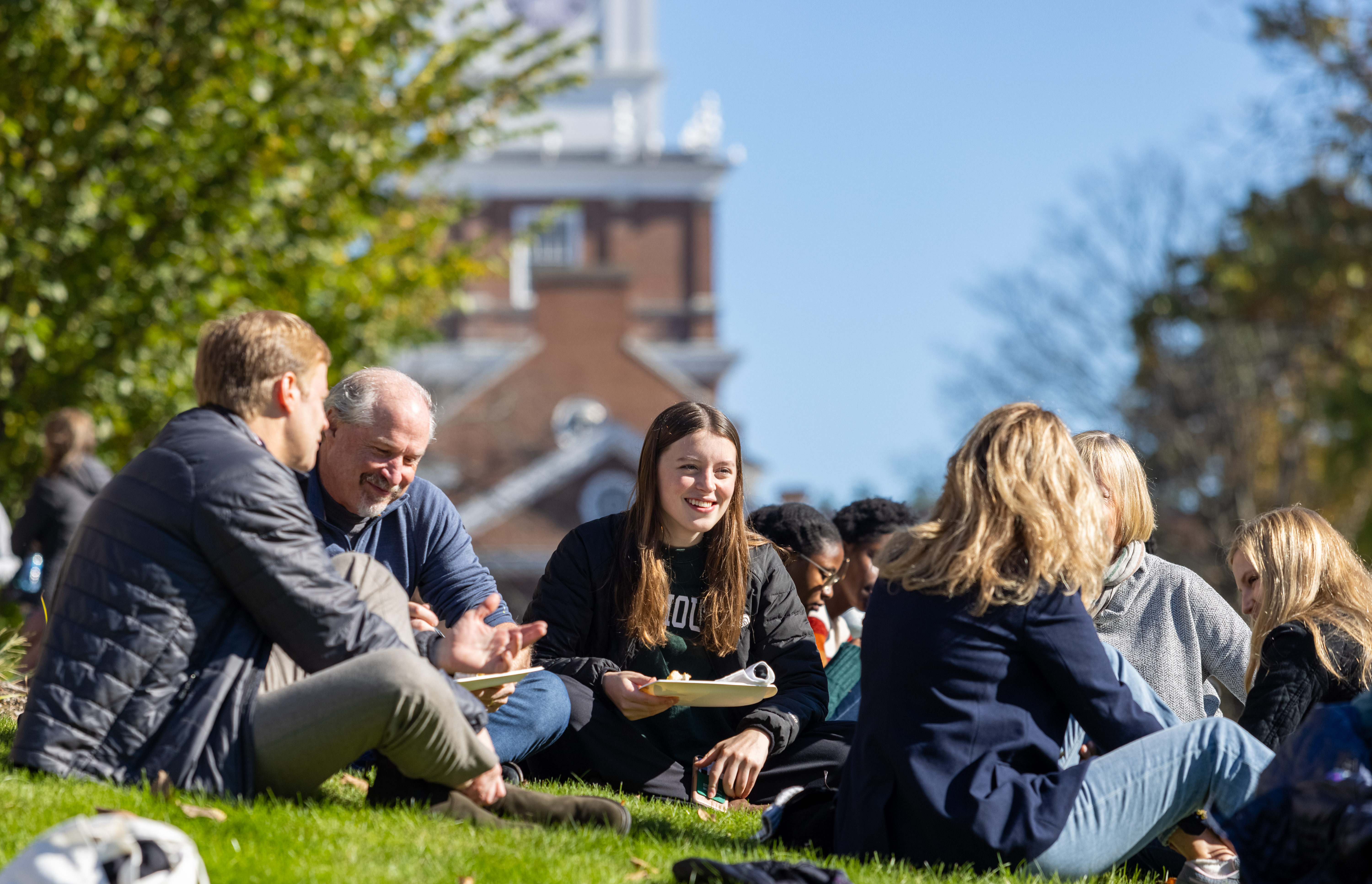 Students and families enjoy a picnic on the green grass at Dartmouth