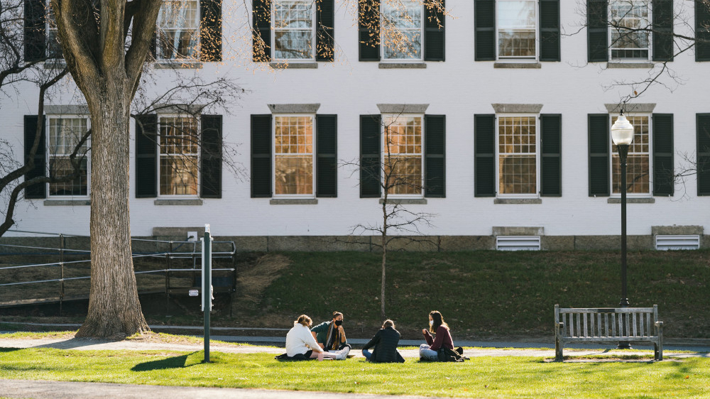 Masked students sitting on the Green across from Dartmouth Row